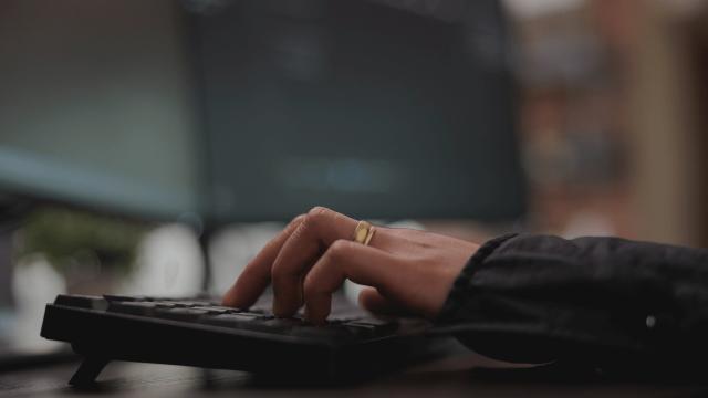 To computer skærme som er forbundet med en Lenovo Dock og en hånd som skriver på keyboardet